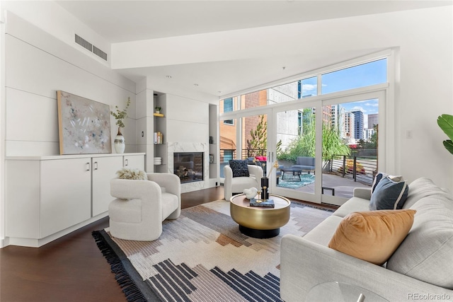 living area featuring a premium fireplace, visible vents, and wood finished floors