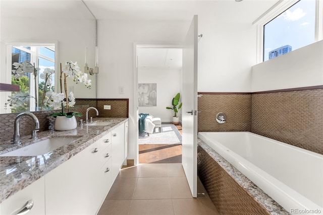 bathroom featuring double vanity, a garden tub, tile patterned flooring, and a sink