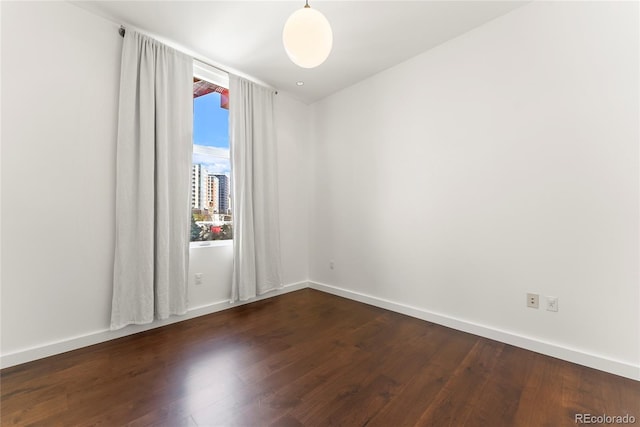 spare room with dark wood-style floors and baseboards