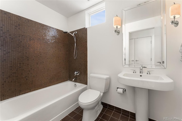 bathroom featuring shower / washtub combination, toilet, a sink, baseboards, and tile patterned floors