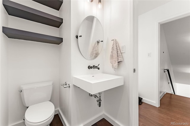 bathroom with baseboards, a sink, toilet, and wood finished floors