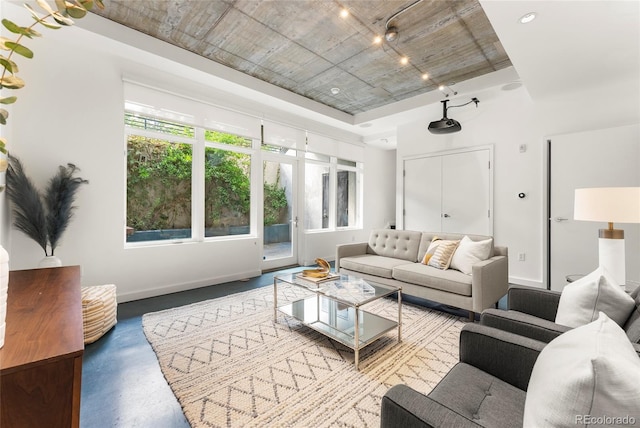 living area featuring concrete flooring and baseboards