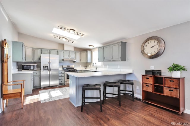 kitchen with lofted ceiling, stainless steel appliances, dark wood-type flooring, and a peninsula