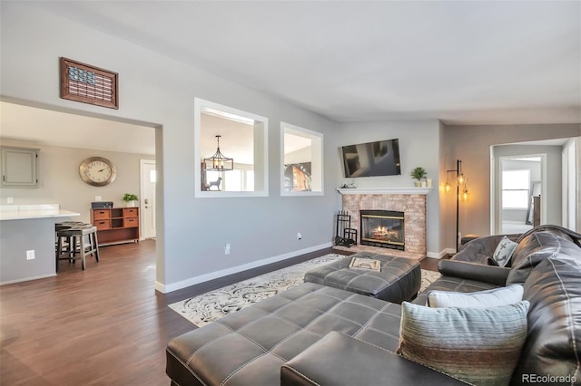 living room with a glass covered fireplace, dark wood finished floors, and baseboards