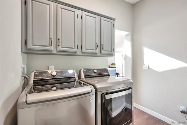 laundry area with cabinet space, baseboards, dark wood-type flooring, and independent washer and dryer