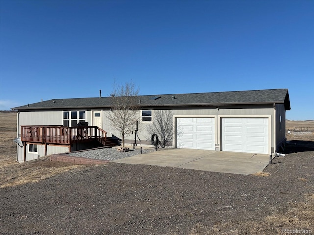 view of front of home with an attached garage, roof with shingles, concrete driveway, and a wooden deck