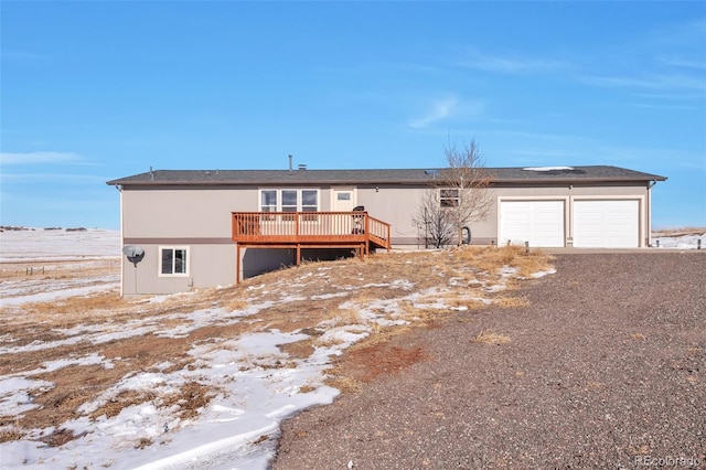 view of front facade featuring an attached garage, a deck, and dirt driveway