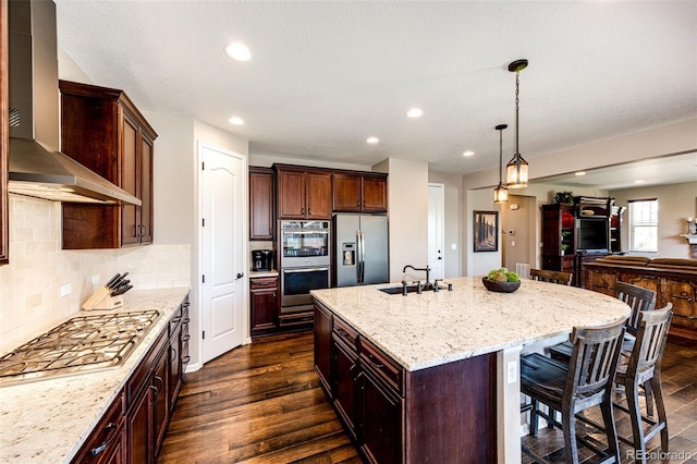 30 S Ider Way, Aurora, CO 80018 - kitchen with appliances with stainless steel finishes, wall chimney range hood, light stone counters, open floor plan, and a center island with sink