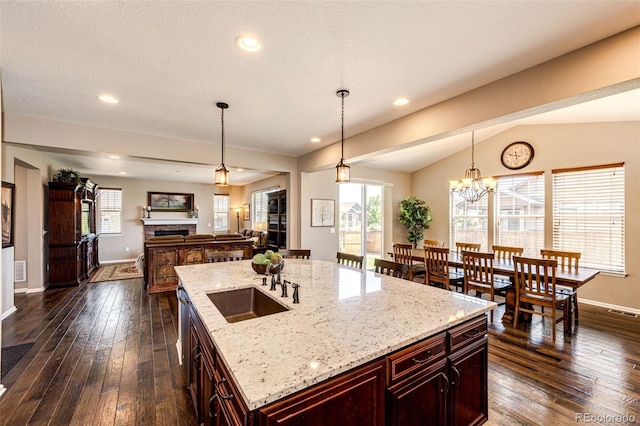 30 S Ider Way, Aurora, CO 80018 - kitchen with reddish brown cabinets, dark wood-style floors, a fireplace, decorative light fixtures, and vaulted ceiling
