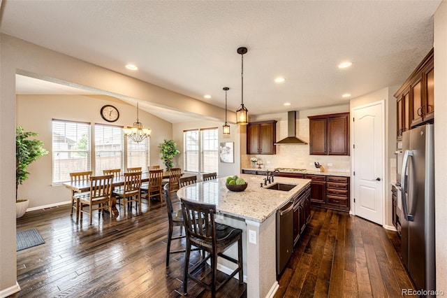 30 S Ider Way, Aurora, CO 80018 - kitchen featuring wall chimney exhaust hood, stainless steel appliances, dark wood-style flooring, a center island with sink, and light stone countertops