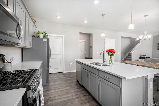 kitchen featuring a center island with sink, dark hardwood / wood-style flooring, stainless steel appliances, sink, and decorative light fixtures