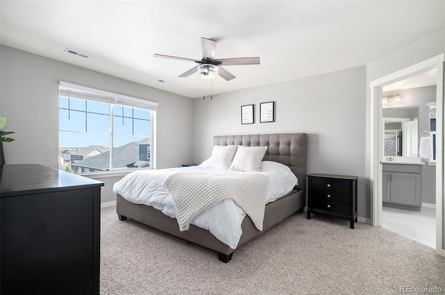 bedroom featuring ensuite bathroom, light colored carpet, and ceiling fan