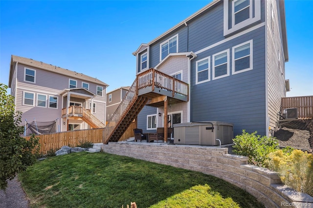 rear view of property with a wooden deck, a patio, a hot tub, central AC unit, and a lawn