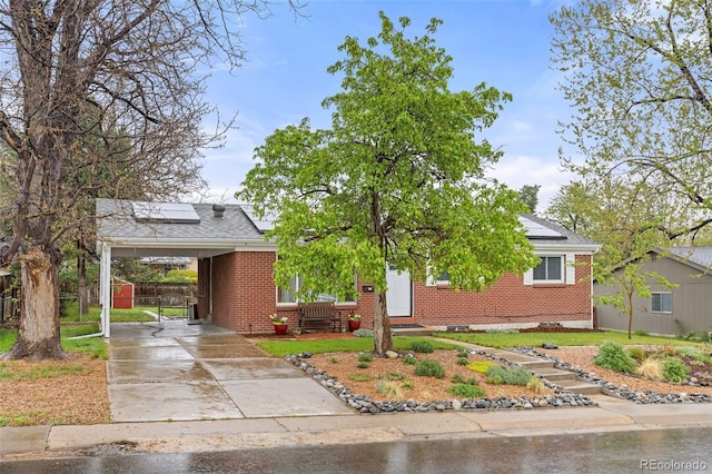 3379 W Wagon Trail Dr, Englewood, CO 80110 - view of front facade with concrete driveway, roof mounted solar panels, brick siding, and a carport