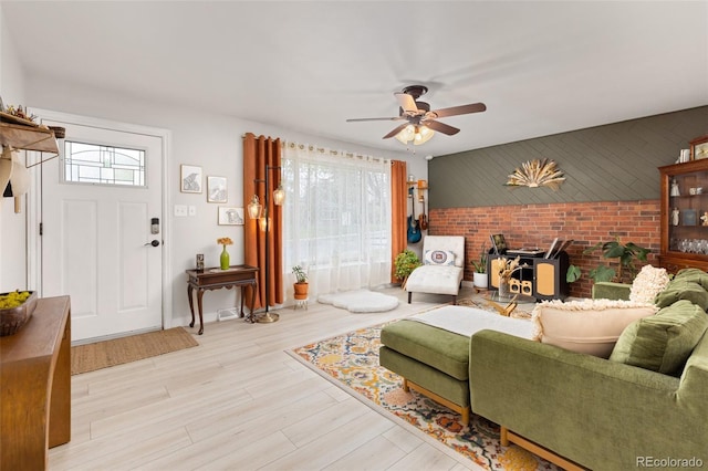 3379 W Wagon Trail Dr, Englewood, CO 80110 - living room featuring plenty of natural light, a wood stove, ceiling fan, brick wall, and wood finished floors