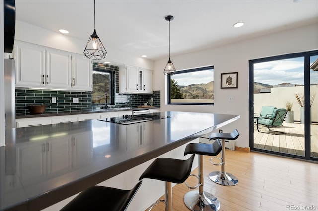 330 Ptarmigan St, Golden, CO 80403 - kitchen with dark countertops, tasteful backsplash, a kitchen bar, light wood-style floors, and recessed lighting