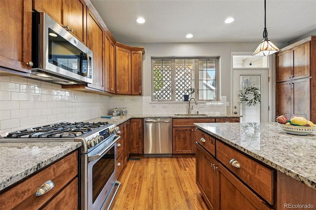 3240 Spruce St, Denver, CO 80238 - kitchen featuring stainless steel appliances, a sink, light wood-style flooring, brown cabinets, and tasteful backsplash