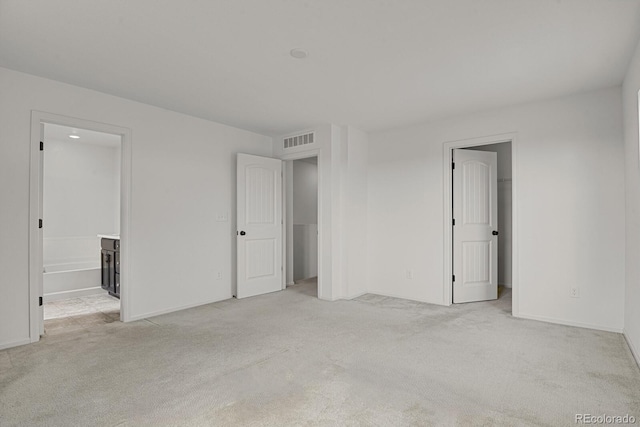 unfurnished bedroom featuring baseboards, a walk in closet, visible vents, and light colored carpet