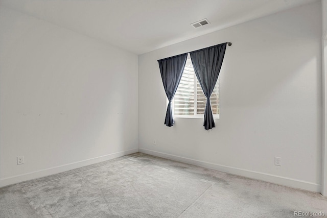 empty room featuring light colored carpet, visible vents, and baseboards