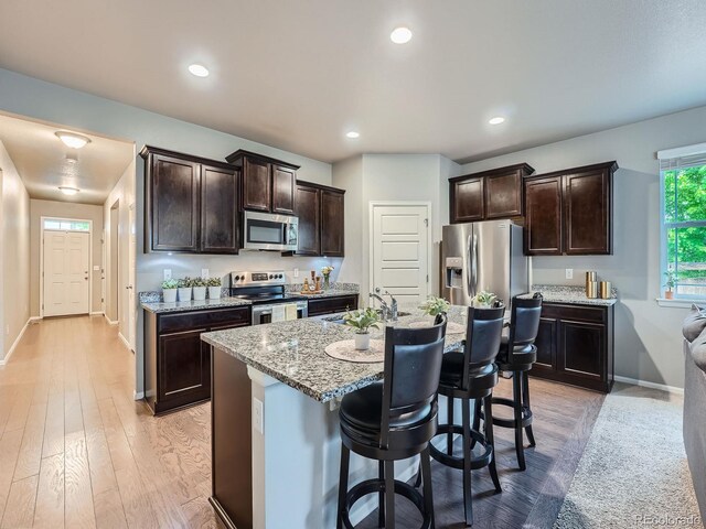 22466 E Layton Cir, Aurora, CO 80015 - kitchen with appliances with stainless steel finishes, baseboards, dark brown cabinetry, light stone countertops, and recessed lighting