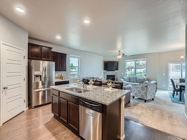 22466 E Layton Cir, Aurora, CO 80015 - kitchen with stainless steel appliances, a sink, dark brown cabinetry, ceiling fan, and a glass covered fireplace
