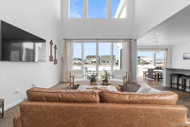 living room with wood-type flooring, a towering ceiling, and an inviting chandelier