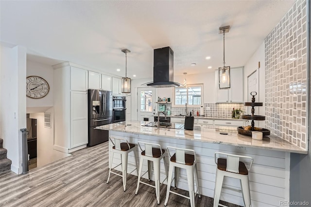 kitchen with stainless steel fridge with ice dispenser, hanging light fixtures, white cabinets, and island exhaust hood