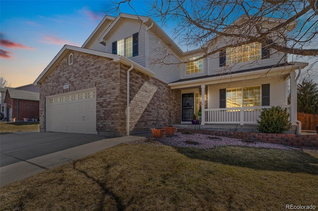 traditional home featuring brick siding, a porch, concrete driveway, a yard, and a garage