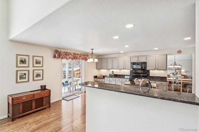 kitchen with gray cabinetry, black microwave, pendant lighting, light wood-style flooring, and electric range