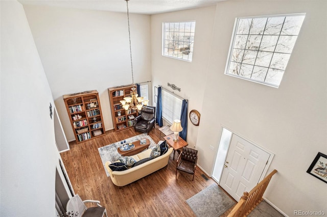 living room with a towering ceiling, baseboards, and wood finished floors