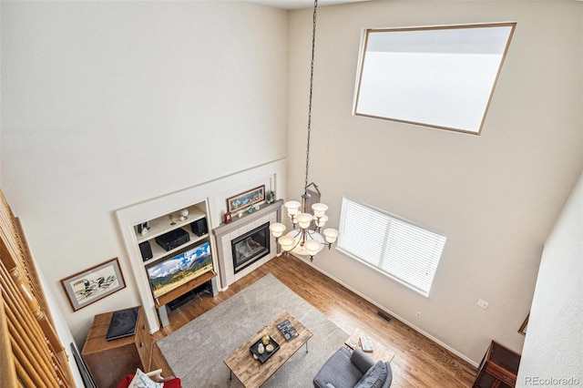 living area with a notable chandelier, wood finished floors, and a tiled fireplace