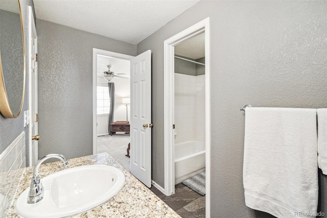 bathroom featuring a textured ceiling, shower / washtub combination, vanity, and a textured wall