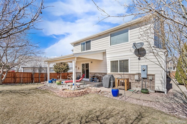 rear view of property with stone siding, fence, and a patio area