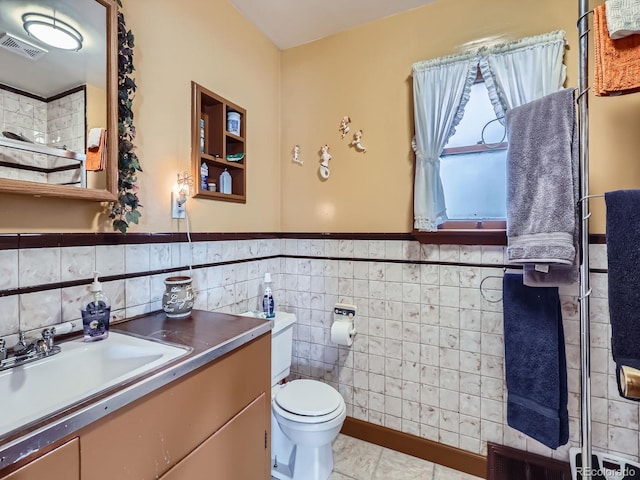 bathroom featuring vanity, tile walls, tile patterned floors, and toilet