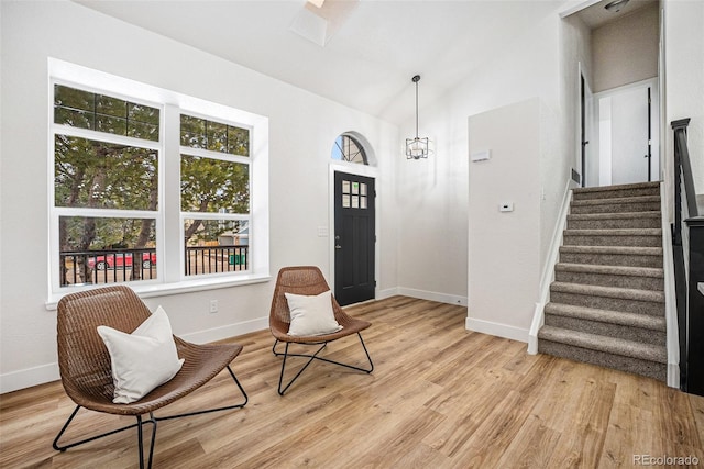 entryway with lofted ceiling, a chandelier, and light wood-type flooring