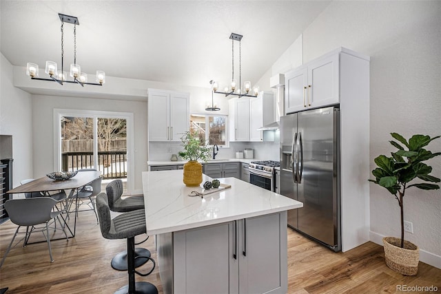 kitchen featuring pendant lighting, sink, lofted ceiling, stainless steel appliances, and a center island