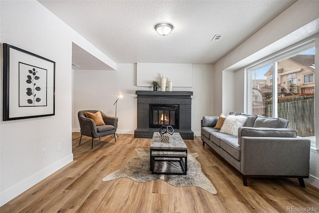 living room featuring a textured ceiling, a fireplace, and light wood-type flooring