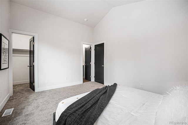 bedroom featuring a walk in closet, lofted ceiling, and carpet flooring