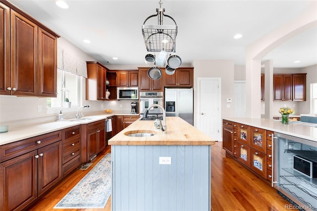 6032 Umber St, Arvada, CO 80403 - kitchen with appliances with stainless steel finishes, a sink, wood finished floors, an island with sink, and recessed lighting