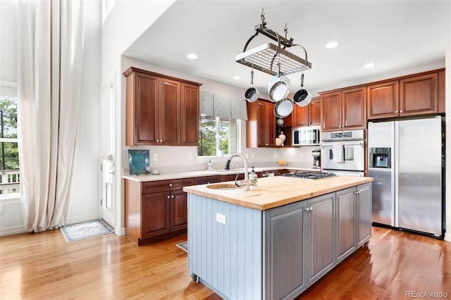 6032 Umber St, Arvada, CO 80403 - kitchen featuring appliances with stainless steel finishes, butcher block counters, a sink, a kitchen island with sink, and light wood-type flooring