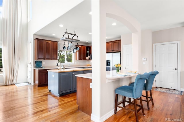 6032 Umber St, Arvada, CO 80403 - kitchen with stainless steel refrigerator with ice dispenser, a center island, arched walkways, light countertops, and light wood-style floors