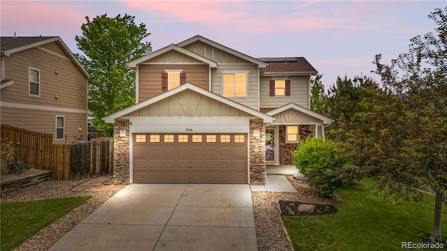 13664 Linden Ct, Thornton, CO 80602 - view of front of house with board and batten siding, driveway, stone siding, roof mounted solar panels, and a garage