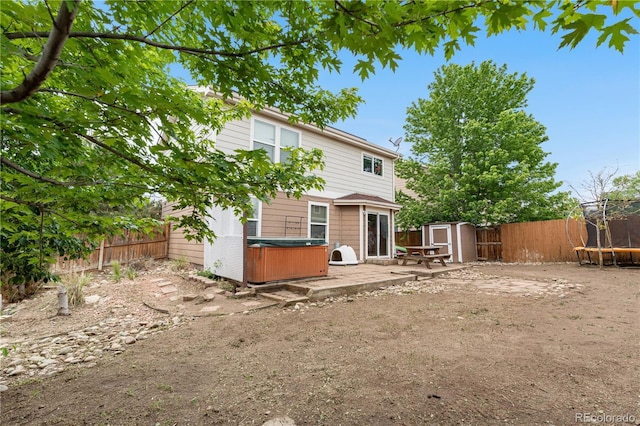 13664 Linden Ct, Thornton, CO 80602 - back of house featuring a trampoline, a hot tub, a fenced backyard, and a patio
