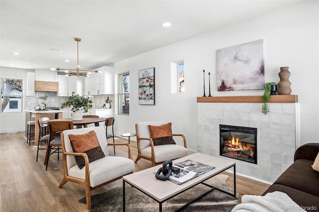 living room featuring light hardwood / wood-style floors, a tile fireplace, and a chandelier