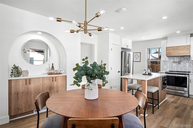 dining space with dark wood-type flooring and an inviting chandelier