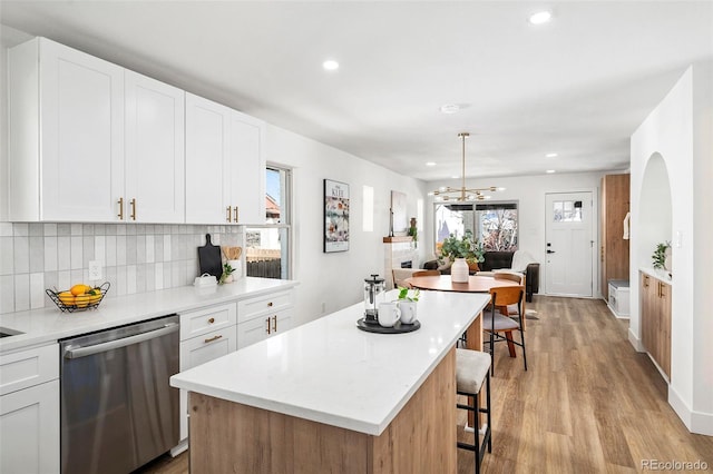 kitchen with stainless steel dishwasher, a center island, pendant lighting, and white cabinets