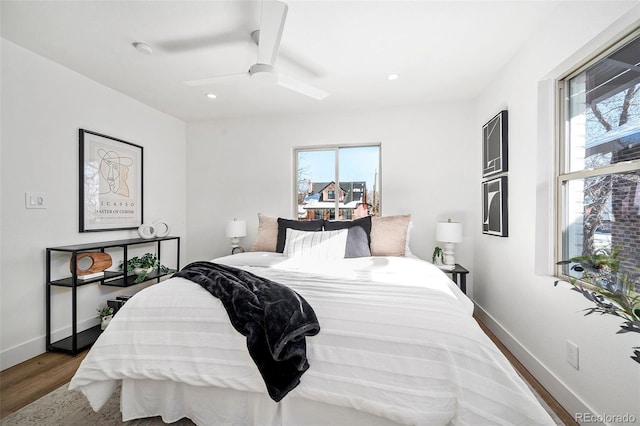 bedroom featuring hardwood / wood-style flooring, ceiling fan, and multiple windows