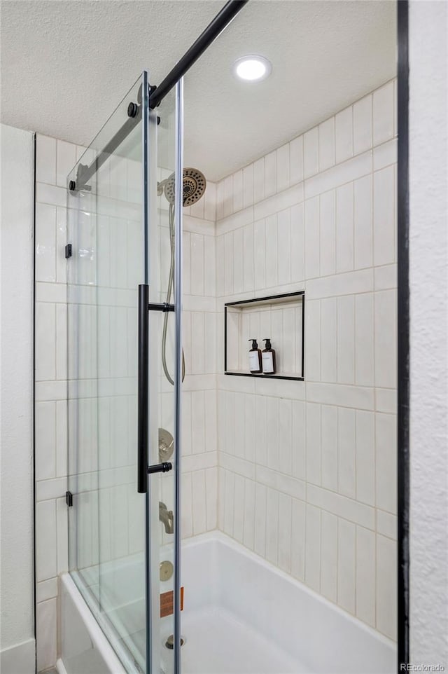 bathroom featuring enclosed tub / shower combo and a textured ceiling