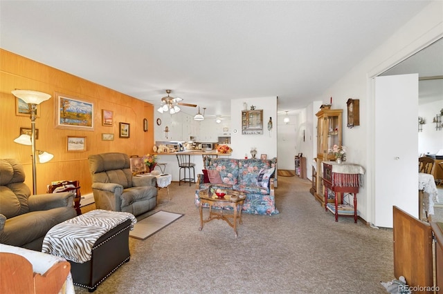 living room featuring wooden walls, carpet floors, and ceiling fan