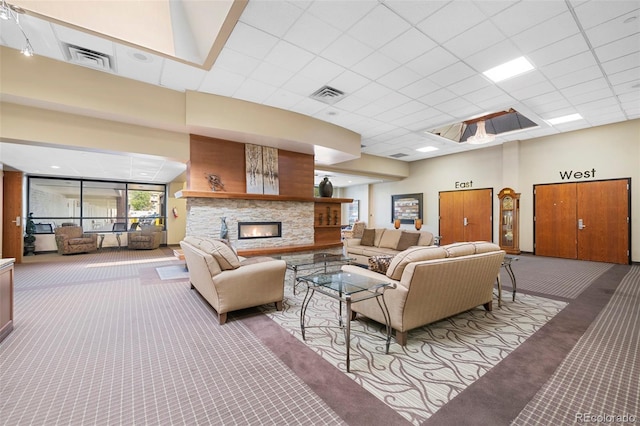 carpeted living room featuring a high ceiling, a stone fireplace, and a paneled ceiling